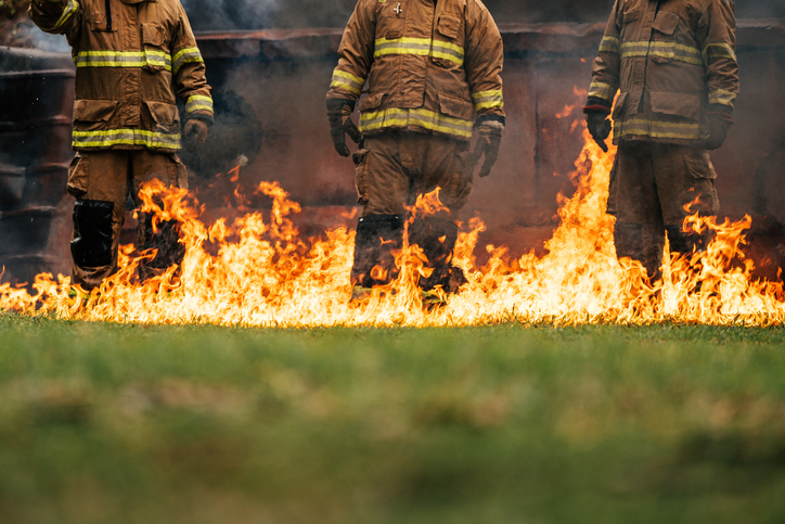 Firefighters standing past live fire in training scenario